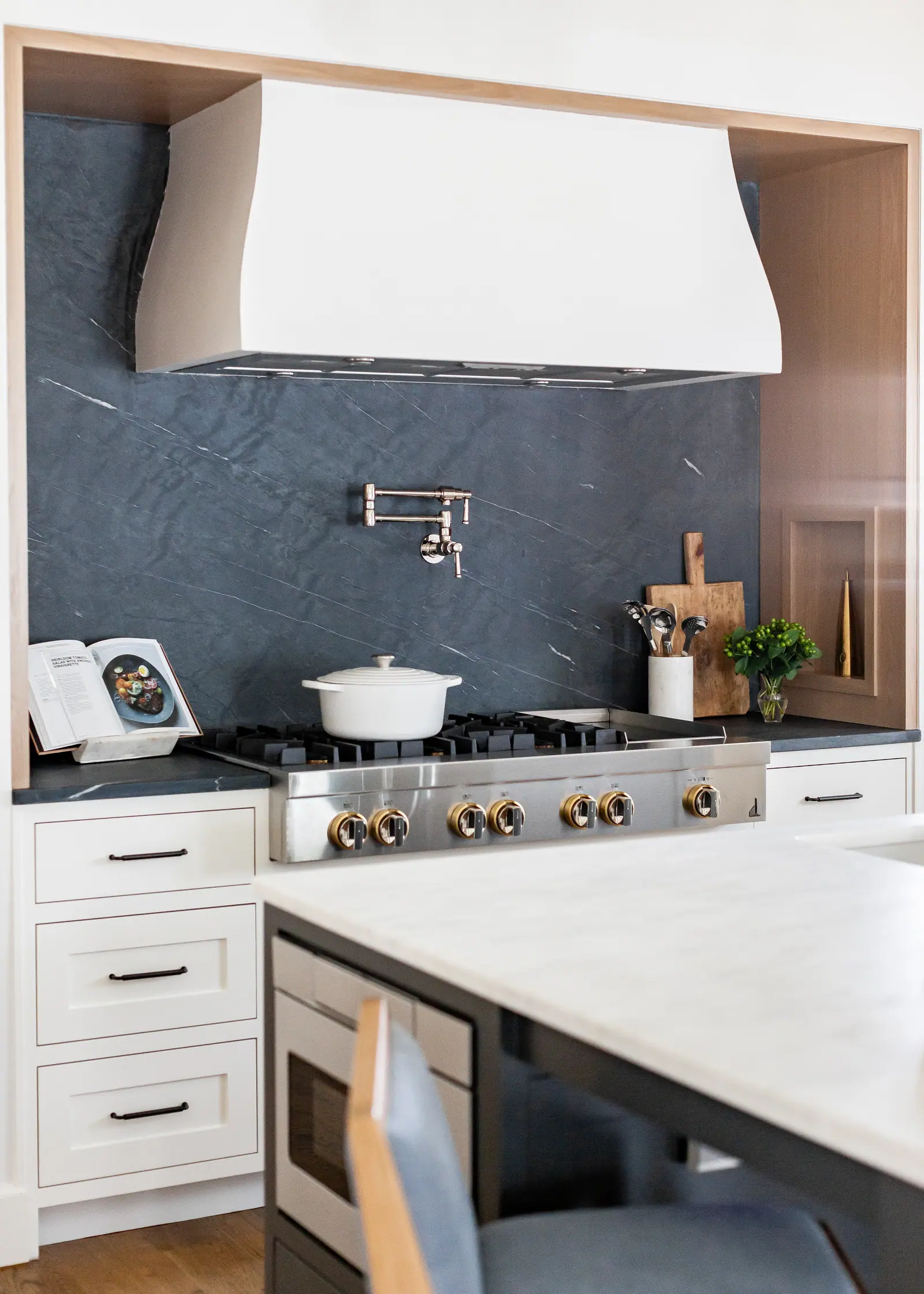 Completed custom kitchen with vaulted timber beams, navy island, and white cabinetry