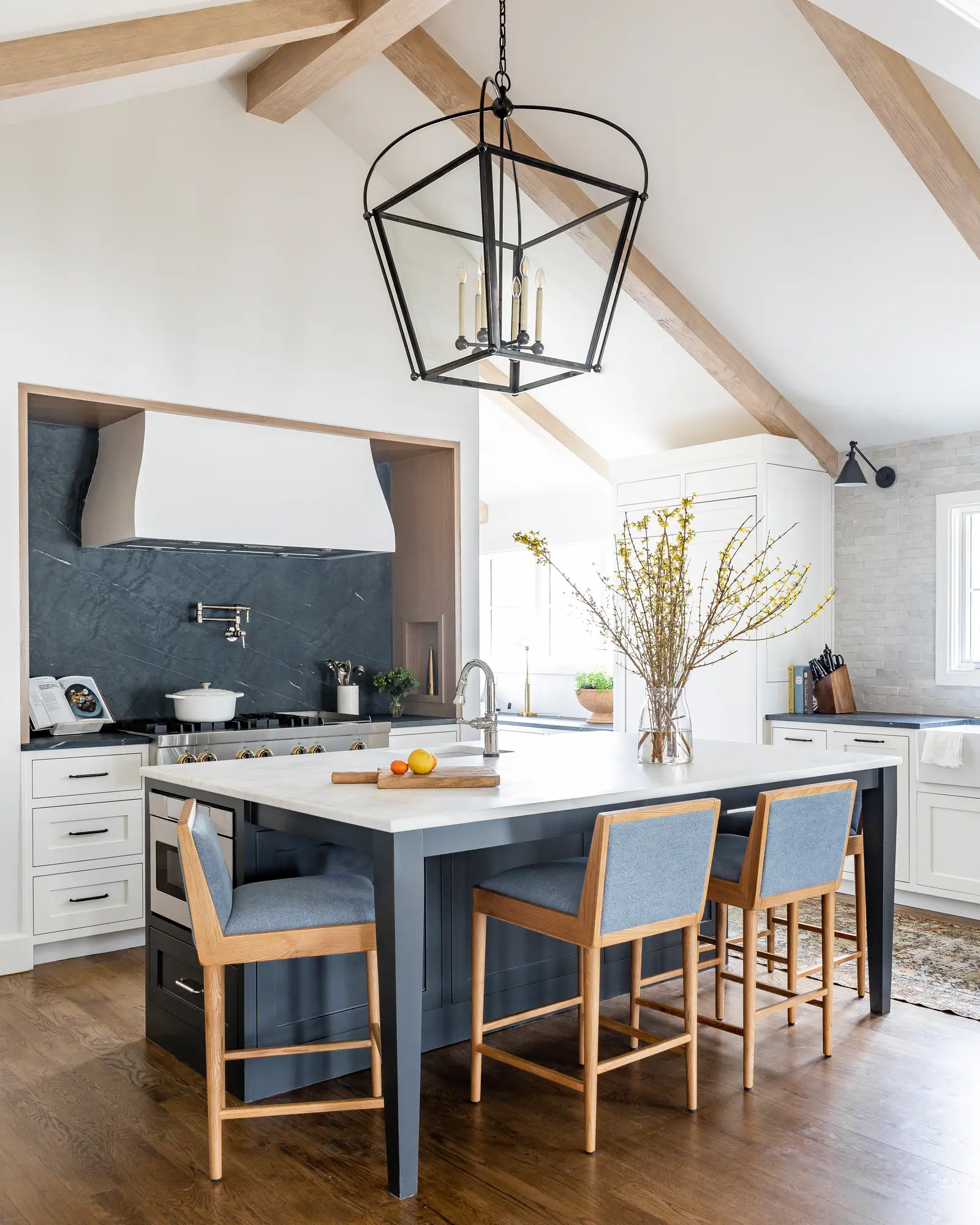 Completed Victorian custom home kitchen with wood beams, navy accents, and an expansive island