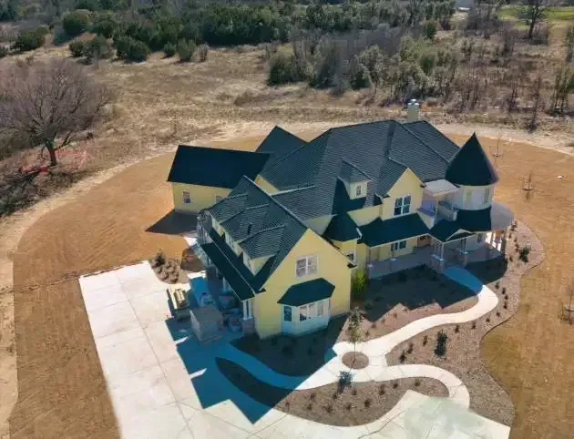 Aerial view of a Victorian-style custom home with turreted rooflines and a curved driveway
